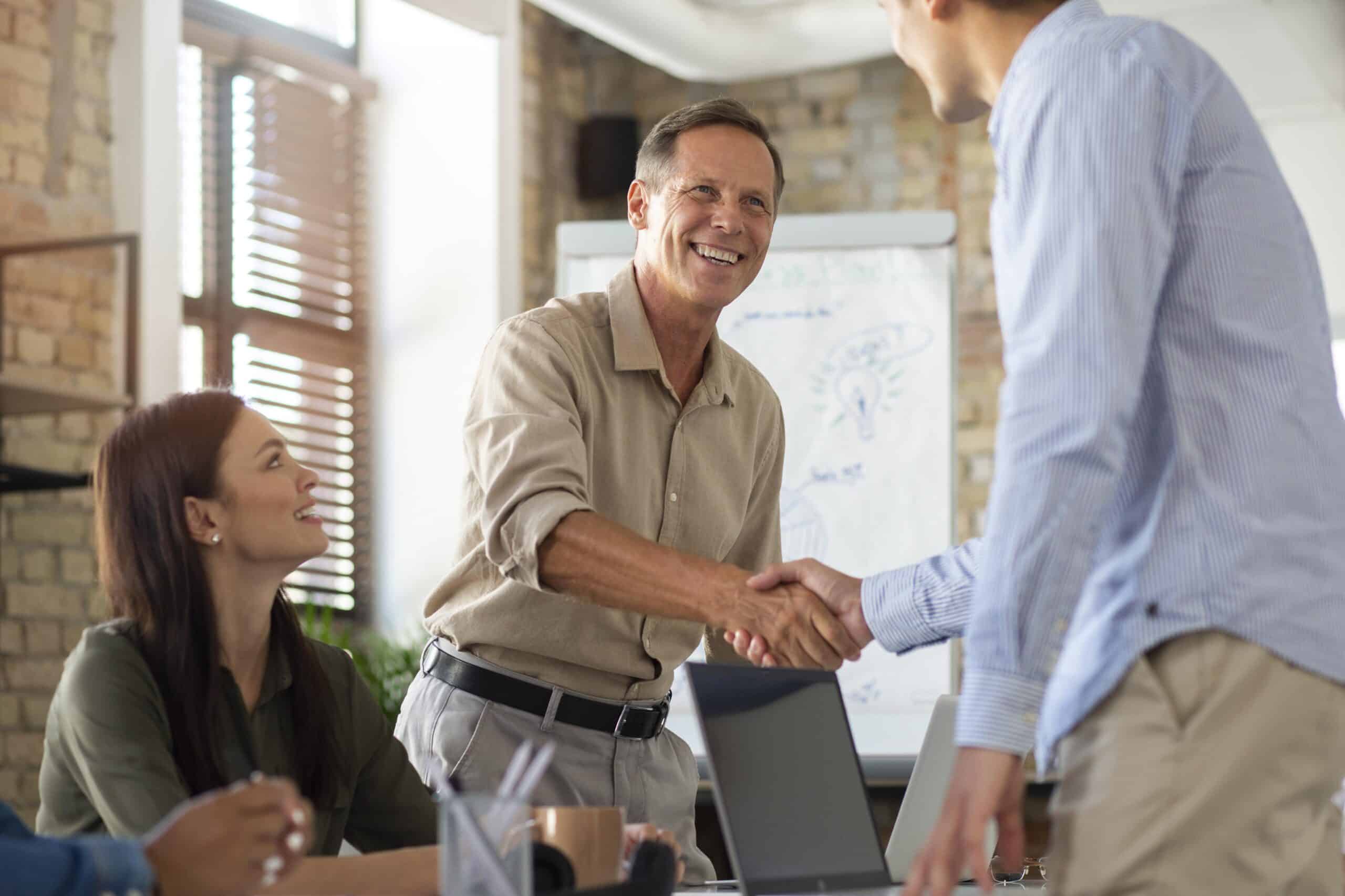 new-corporate-members-sibn-smiles-teamwork-in-a-meeting-room A man smiles and shakes hands with a new SIBN member in a meeting room
